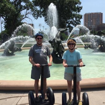 a couple in front of fountain on their segways